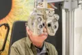 Client lors d'un examen de la vue au réfracteur chez Churchill Optique à Uccle